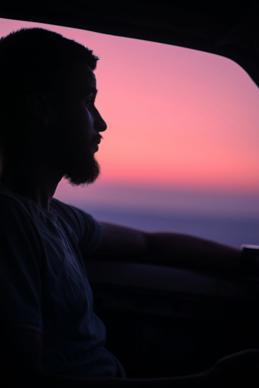 man in car sunrise reflection window